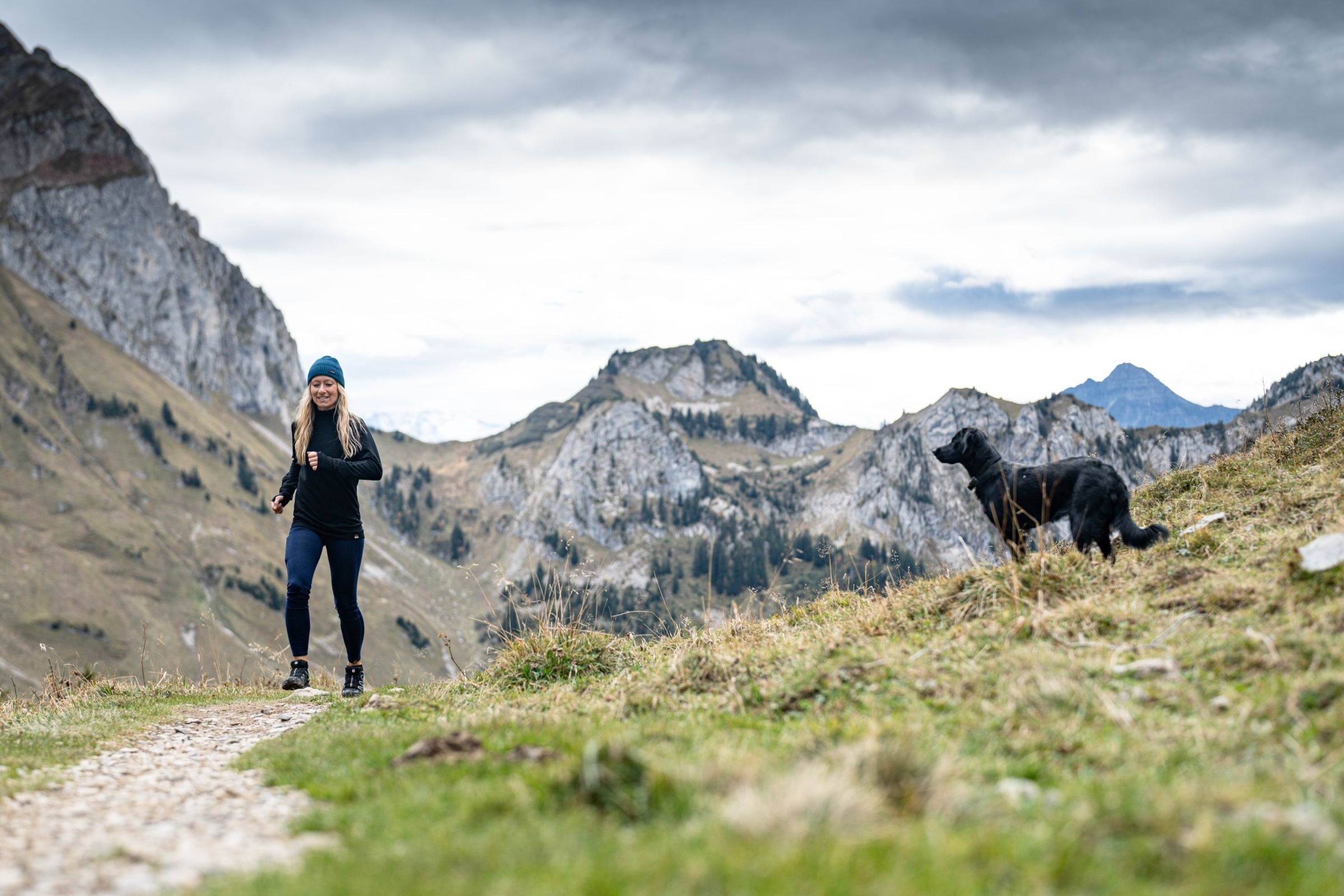 Woman trail running with a dog in a the mountains
