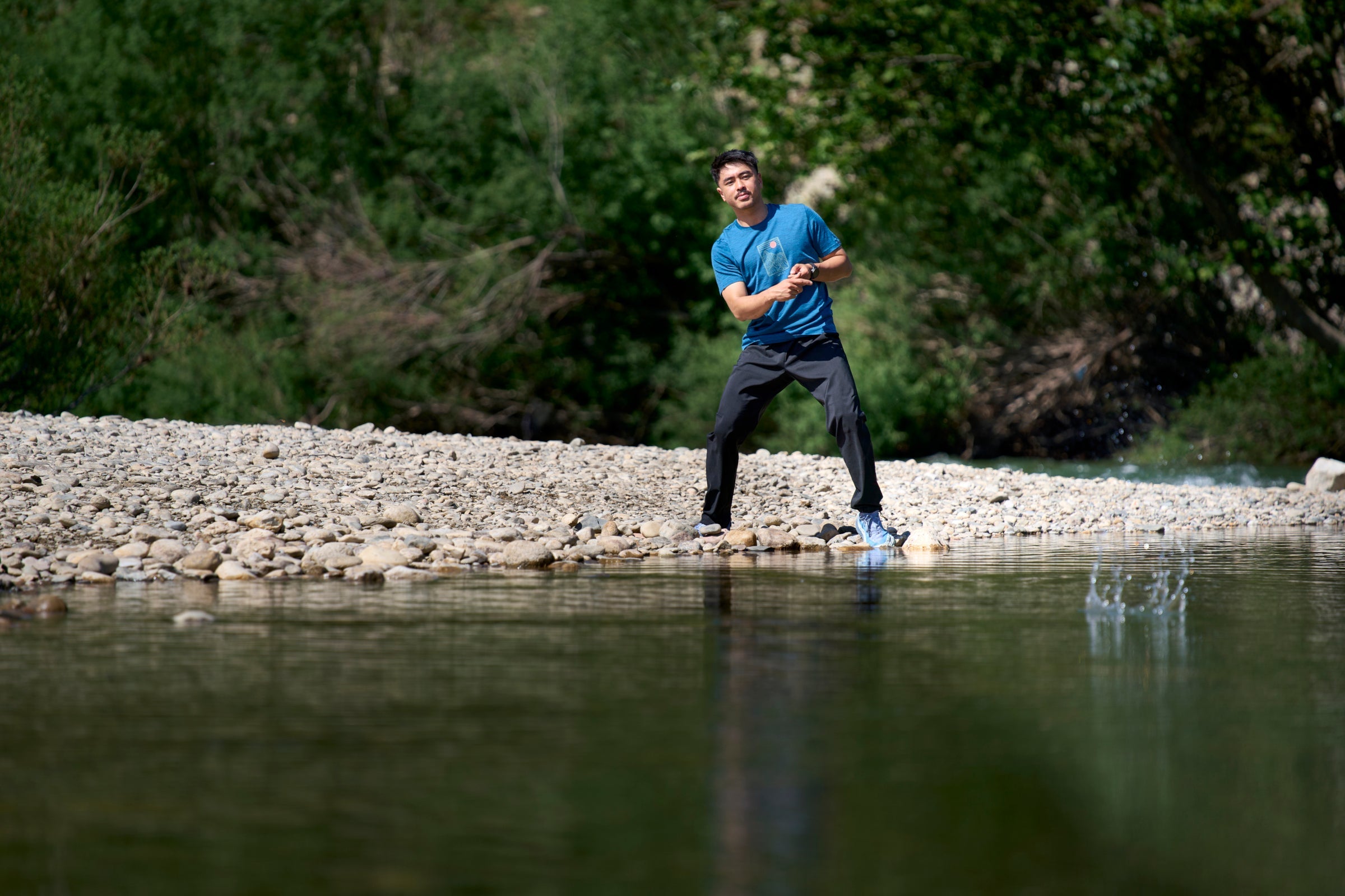 Man standing on rocks by a river
